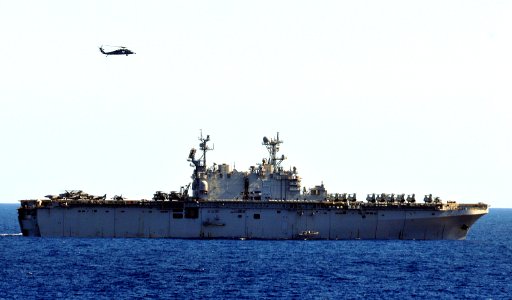 US Navy 101213-N-7948R-001 An MH-60S Sea Hawk helicopter flies over the amphibious assault ship USS Peleliu (LHA 5) during flight operations