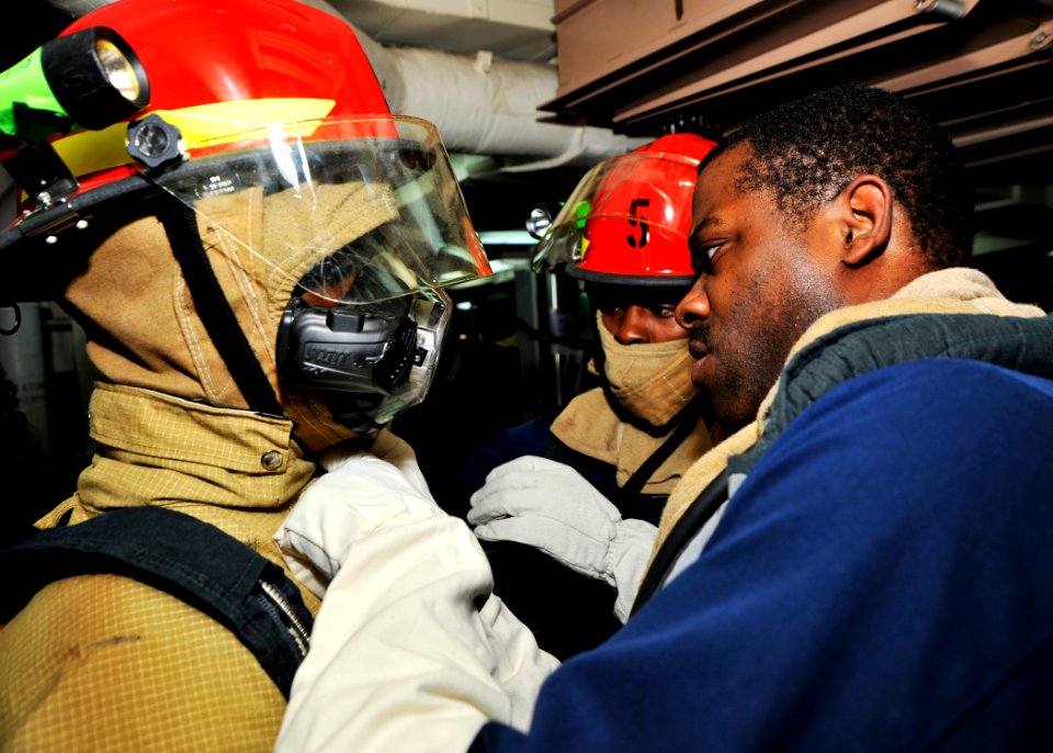 US Navy 101215-N-6499D-054 ulinary Specialist 2nd Class Roderick Bass, right, and Culinary Specialist 3rd Class Dontavia Timmons, center, assist Da
