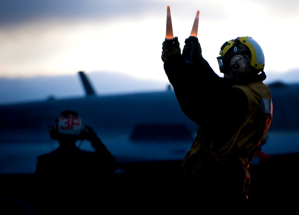 US Navy 101215-N-2055M-265 An aircraft director guides an F-A-18F Super Hornet assigned to Strike Fighter Squadron (VFA) 22 to a catapult on the fl