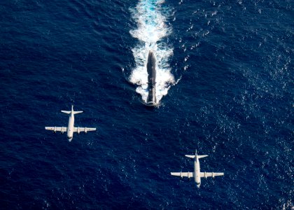 US Navy 101210-N-6720T-221 Japan Maritime Self Defense Force and U.S. P-3 Orion patrol craft fly over the Los Angeles-class attack submarine USS Ho