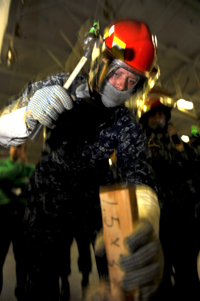US Navy 101214-N-2475A-159 Aviation Electronics Technician Airman Apprentice Jonathan Mast hammers a wooden wedge in place for a soft patch during