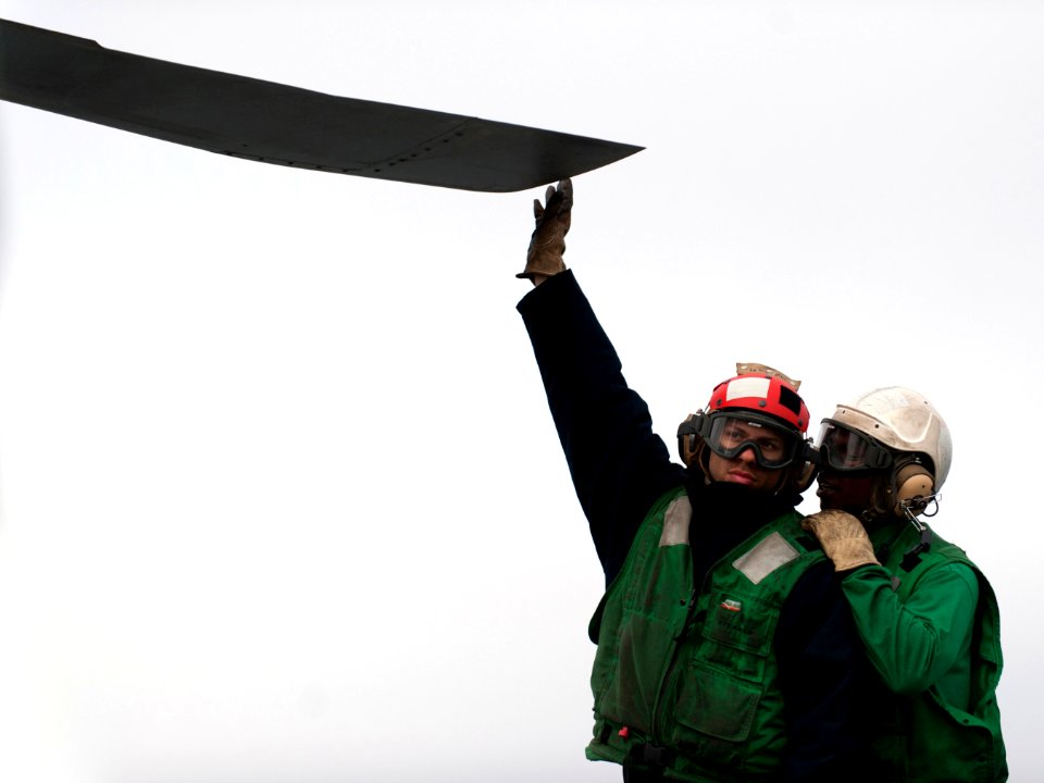 US Navy 101210-N-7981E-095 Aviation Structural Mechanic 2nd Class Ahkyi Derricks, right, communicates instructions to Aviation Structural Mechanic
