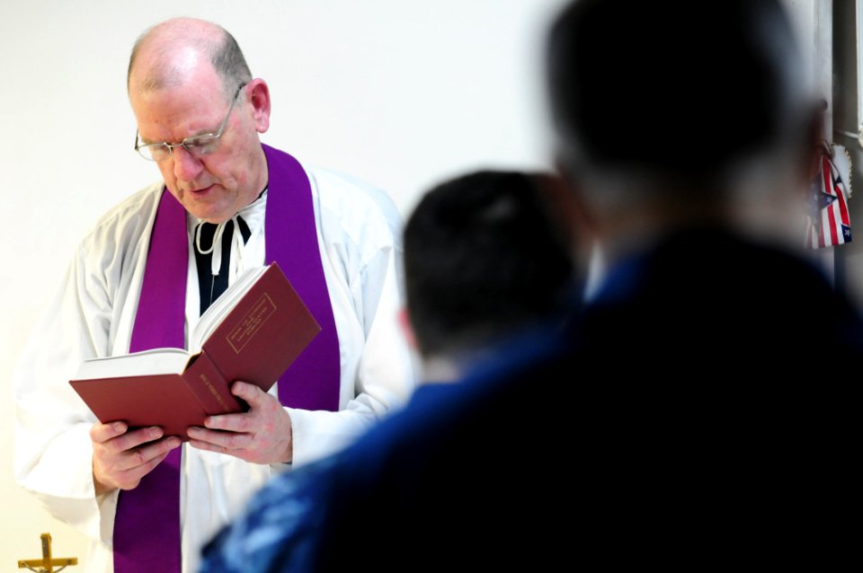 US Navy 101212-N-3659B-071 Cmdr. Kevin Deeley, a catholic priest, sings a hymn during catholic mass aboard the amphibious dock landing ship USS Com