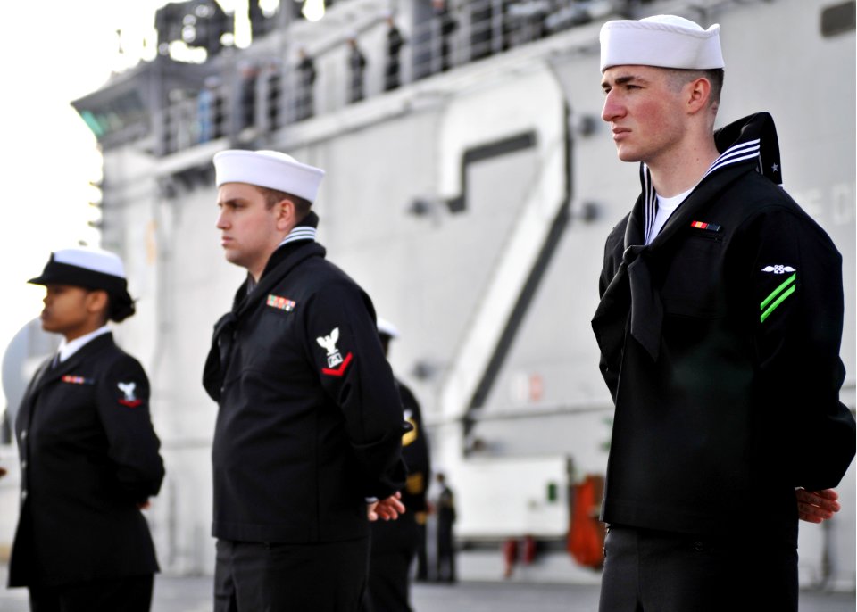 US Navy 101214-N-9950J-119 Aviation Boatswain's Mate (Fuel) Airman Apprentice Carlos Quinlan, right, mans the rails aboard the forward-deployed am