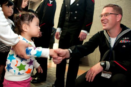 US Navy 101212-N-5758H-024 Musician 2nd Class John Wylie, assigned to the U.S. 7th Fleet Band, Far East Edition, shakes hands with a girl after th