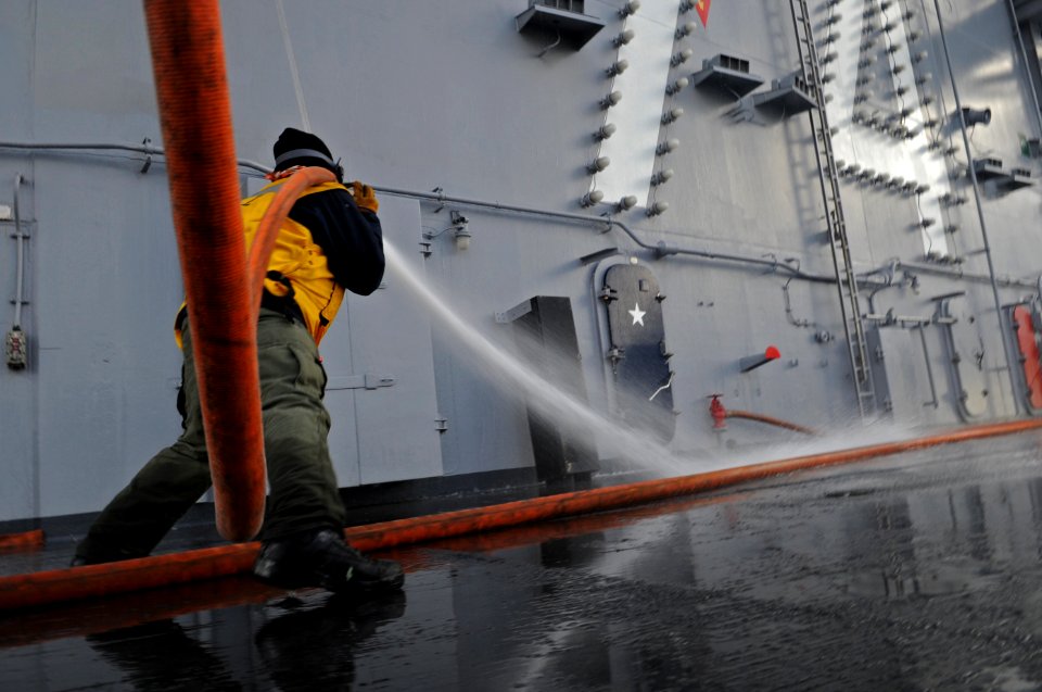 US Navy 101216-N-5031T-144 A Sailor handles a hose during an aqueous film forming foam scrub down on the flight deck aboard the aircraft carrier US