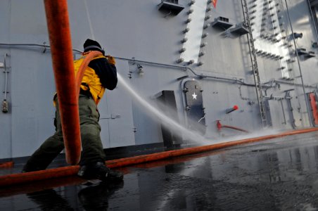 US Navy 101216-N-5031T-144 A Sailor handles a hose during an aqueous film forming foam scrub down on the flight deck aboard the aircraft carrier US