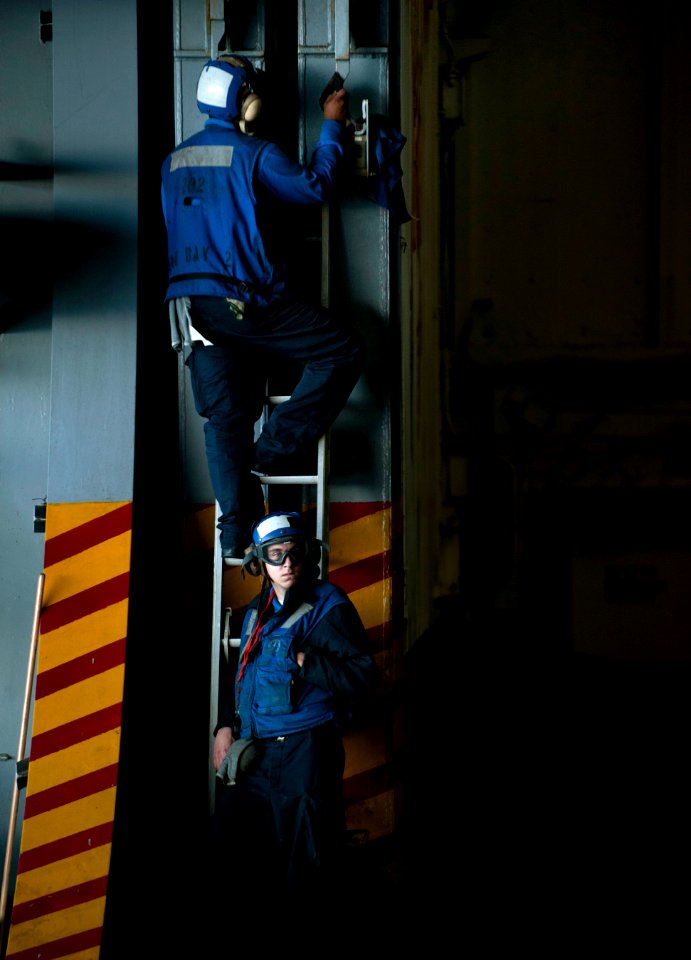 US Navy 101218-N-7981E-158 Aviation Boatswain's Mate Airman Randy Davies, top, and Aviation Boatswain's Mate Airman Jason Young perform corrosion c