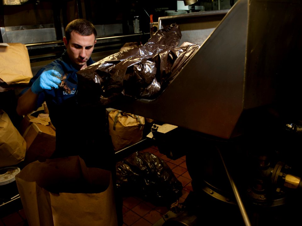 US Navy 101213-N-7981E-078 Damage Controlman Fireman Recruit Francisco Deanda removes solid items from food waste before running it through a pulpe