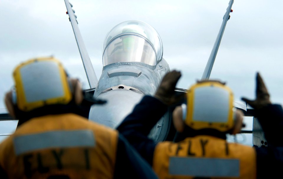 US Navy 101217-N-7981E-367 Aircraft directors guide an F-A-18C Hornet across the flight deck of the aircraft carrier USS Carl Vinson (CVN 70)