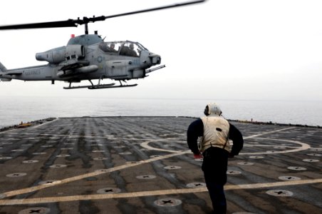 US Navy 101215-N-3659B-013 Boatswain's Mate 1st Class Adam Cohen braces himself as a AH-1 Cobra helicopter approaches USS Comstock (LSD 45)