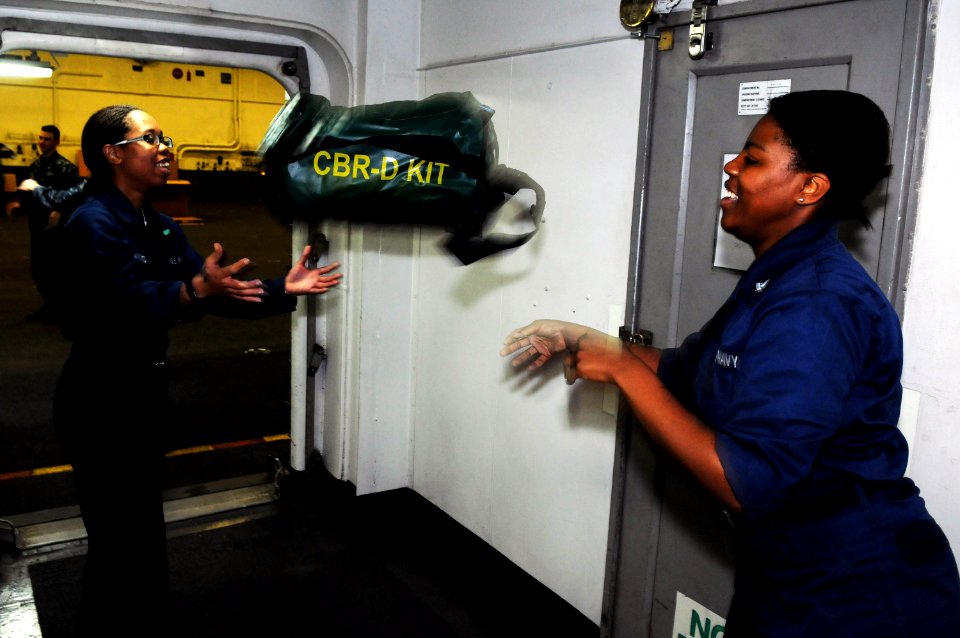 US Navy 101216-N-0232G-065 Aviation Boatswain's Mate (Equipment) 3rd Class Elizabeth Irby, right, passes a chemical, biological and radiological ga
