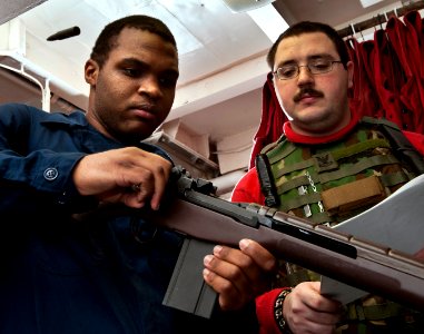 US Navy 101219-N-7981E-060 unner's Mate Seaman Anthony Crutchfield, left, ejects an inert training round from an M-14 rifle during general weapons photo