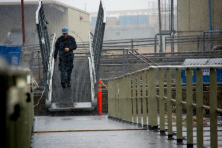 US Navy 101221-N-9643K-383 A Sailor assigned to the amphibious assault ship USS Bonhomme Richard (LHD 6) walks the causeway between the ship and th