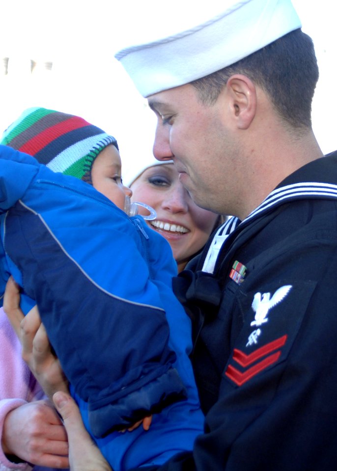 US Navy 101223-N-5292M-180 Hull Maintenance Technician 2nd Class Woren Walken greets his wife and seven-month-old son during a homecoming celebrati