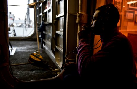 US Navy 101221-N-7981E-606 Aviation Boatswain's Mate (Fuel) Airman Spenser Hood communicates with a fuel pump room via a sound-powered phone from a