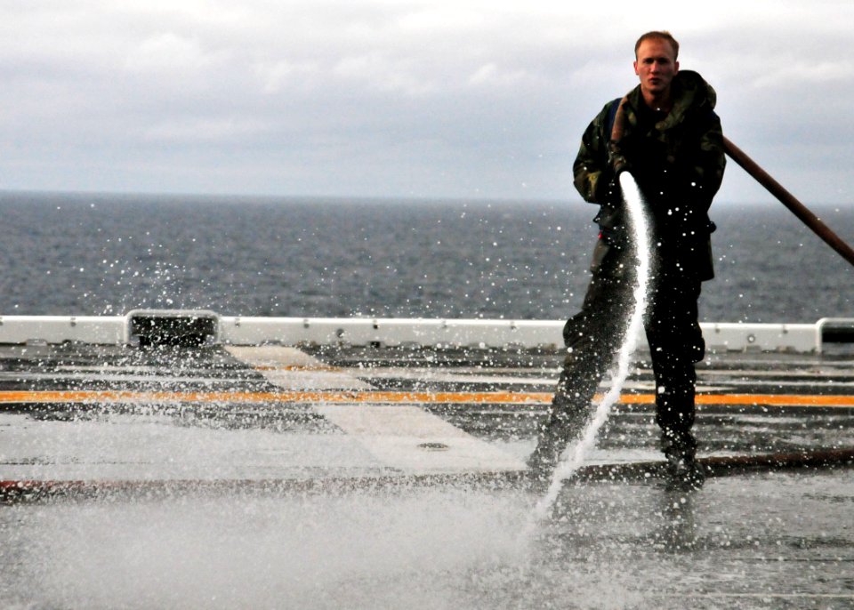 US Navy 101217-N-1722W-045 Aviation Boatswain's Mate (Handling) Airman Jacob Long, from Godfrey, Ill., washes down the flight deck of the amphibio