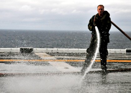 US Navy 101217-N-1722W-045 Aviation Boatswain's Mate (Handling) Airman Jacob Long, from Godfrey, Ill., washes down the flight deck of the amphibio