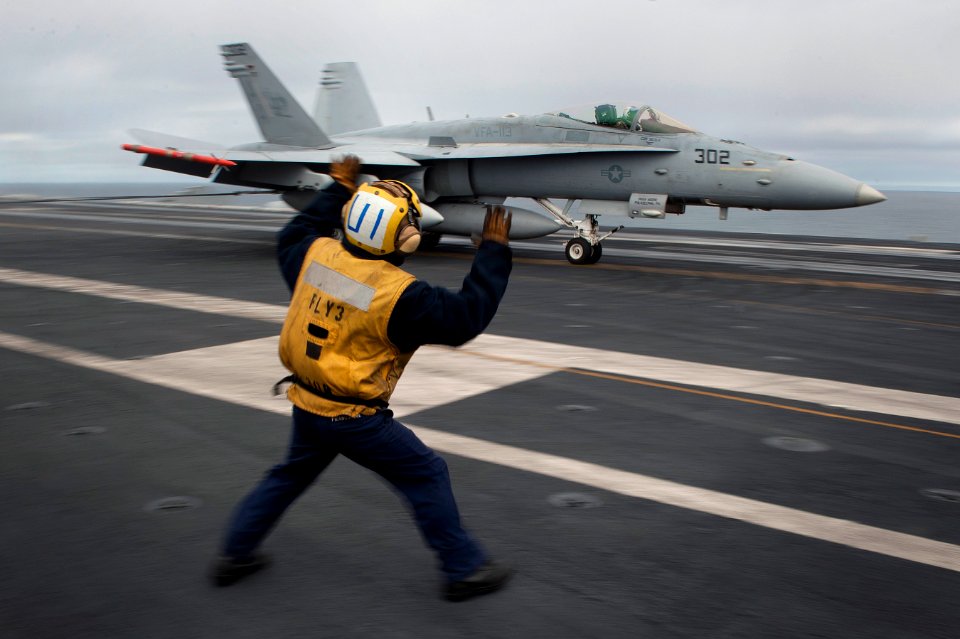 US Navy 101217-N-7981E-135 Aviation Boatswain's Mate (Handling) Airman Miguel Pizanojaime rushes into the landing area to direct the pilot of an F