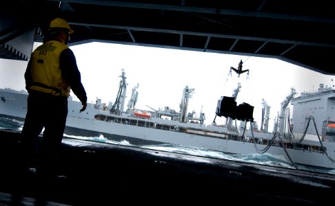 US Navy 101221-N-2055M-081 Boatswain's Mate 3rd Class Christopher Cook watches stores cross from the Military Sealift Command fleet replenishment o