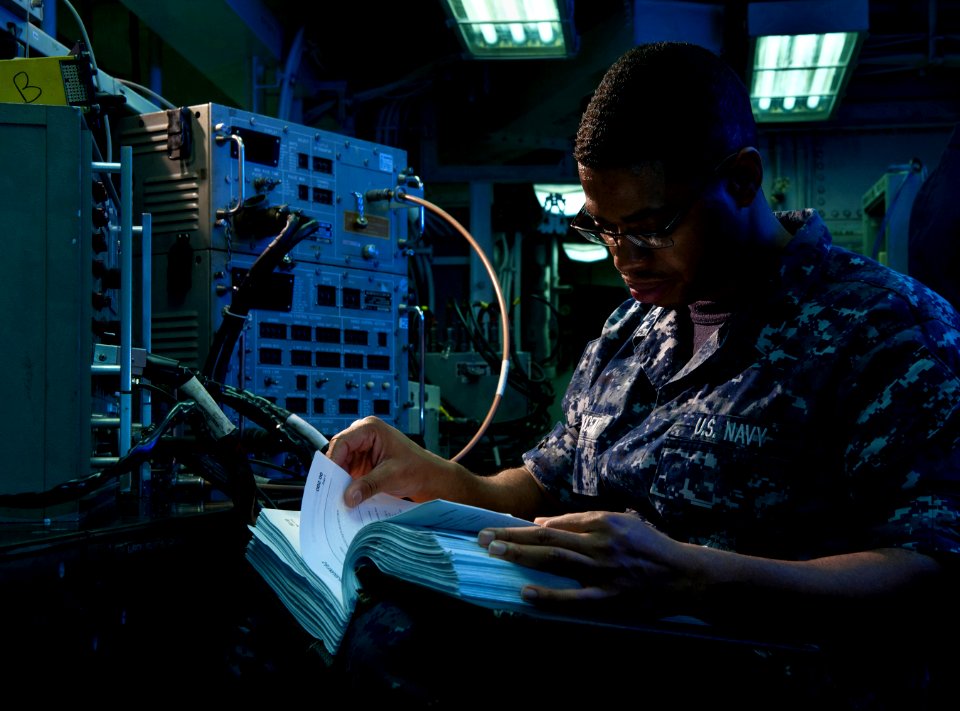 US Navy 101218-N-7981E-275 Aviation Electronics Technician Airman Stouweed Innocent refers to a technical manual while troubleshooting a tactical a