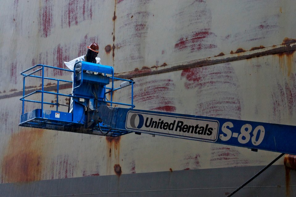 US Navy 101221-N-9643K-452 A NASSCO shipyard worker uses a lift to continue working on the hull of the amphibious assault ship USS Bonhomme Richar