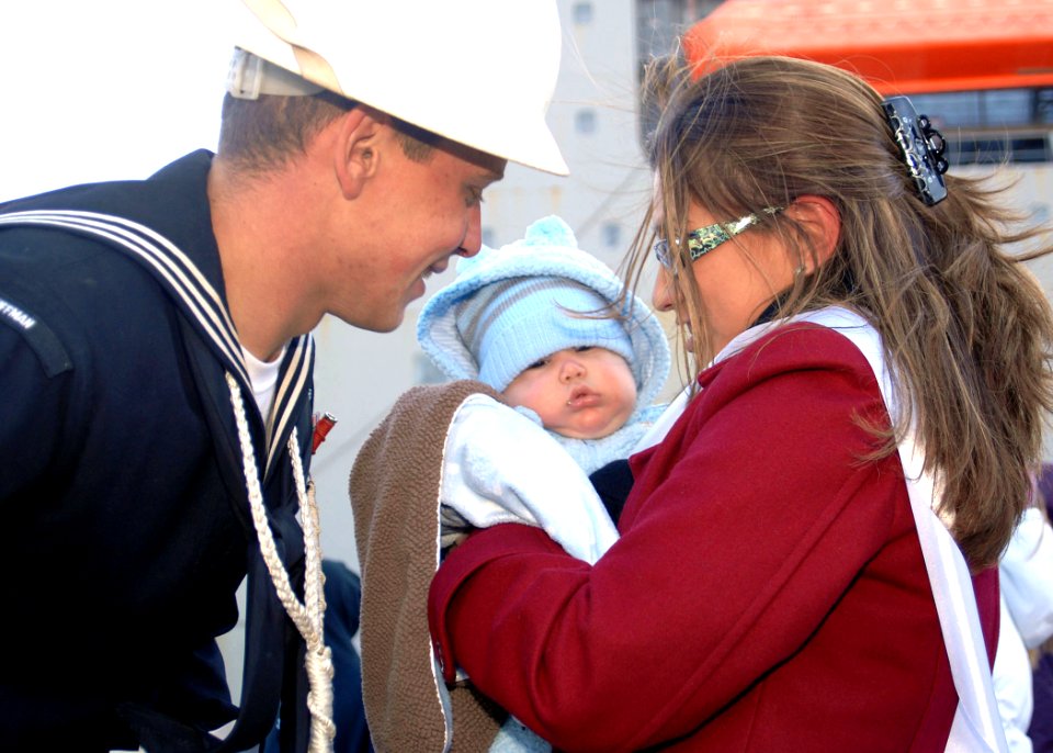 US Navy 101223-N-5292M-174 Boatswain's Mate 3rd Class Jonathan Levai greets his wife and four-month-old son during a homecoming celebration for the