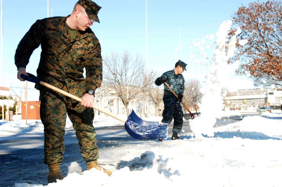 US Navy 101228-N-7004H-001 Lance Cpl. William J. Snyder, left, and Mass Communication Specialist 1st Class Darryl Wood clear snow off the sidewalk