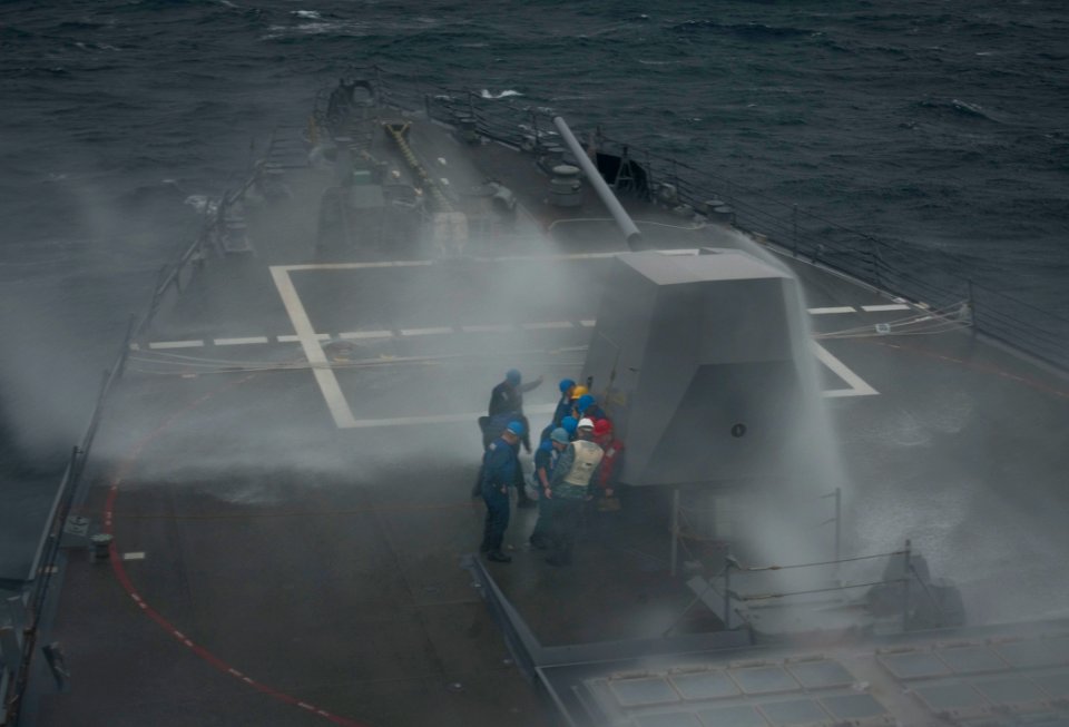 US Navy 110126-N-9589S-016 Sailors seek cover from sea spray behind an MK-45 5-inch-54-caliber gun aboard USS Truxtun (DDG 103)