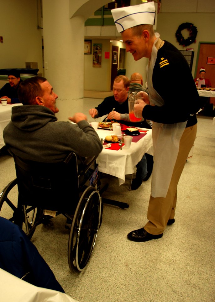 US Navy 101225-N-7642M-106 Lt. Cmdr. Anthony Savage, executive officer of USS Constitution, serves Juice and chats to a veteran at the New England
