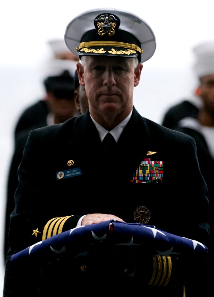 US Navy 101227-N-2055M-488 Capt. Bruce H. Lindsey walks with the national ensign during a burial at sea aboard USS Carl Vinson (CVN 70)