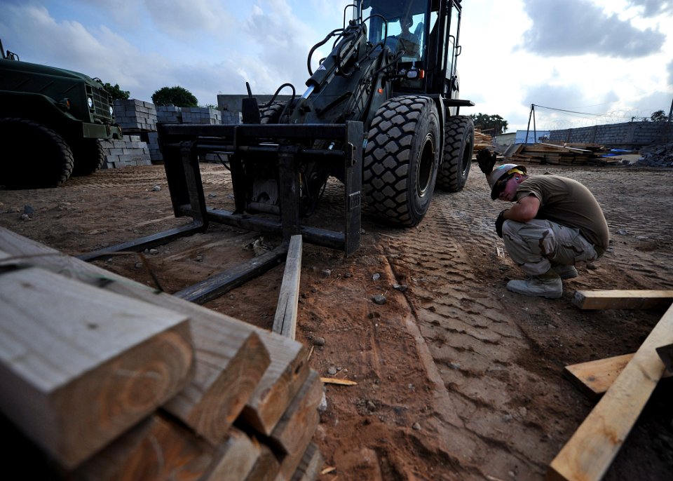 US Navy 110118-N-4440L-079 Equipment Operator Constructionman Kyle Holtzman directs Equipment Operator Constructionman Eric Hofmans as he operates