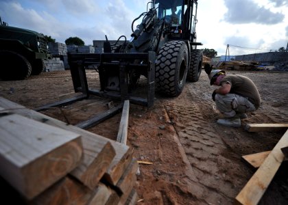 US Navy 110118-N-4440L-079 Equipment Operator Constructionman Kyle Holtzman directs Equipment Operator Constructionman Eric Hofmans as he operates photo