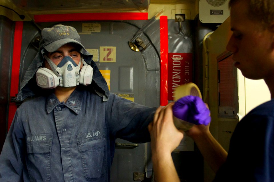 US Navy 110127-N-9643K-412 A Sailor assigned to the amphibious assault ship USS Bonhomme Richard (LHD 6) tapes gaps in his clothing before painting