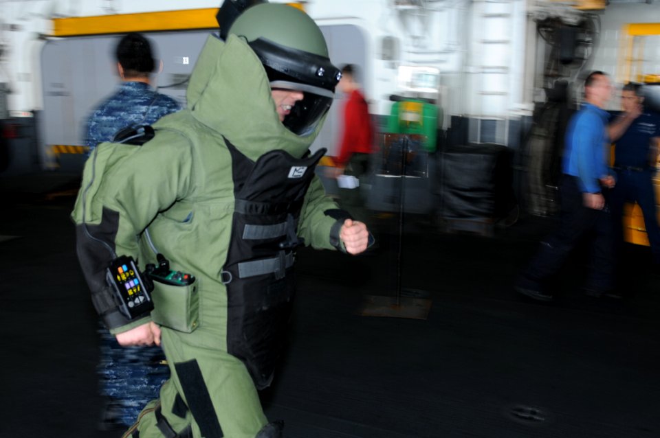US Navy 110123-N-2908M-037 viation Ordnanceman 2nd Class Matthew Bolton tests his mobility while in a bomb suit during training aboard USS Kearsarg