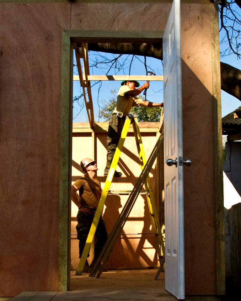 US Navy 110127-N-6724S-249 Builder 2nd Class Andreas Toth, left, helps a Guatemalan Jefatura de Mantenimiento sailor nail the roof support of a sou