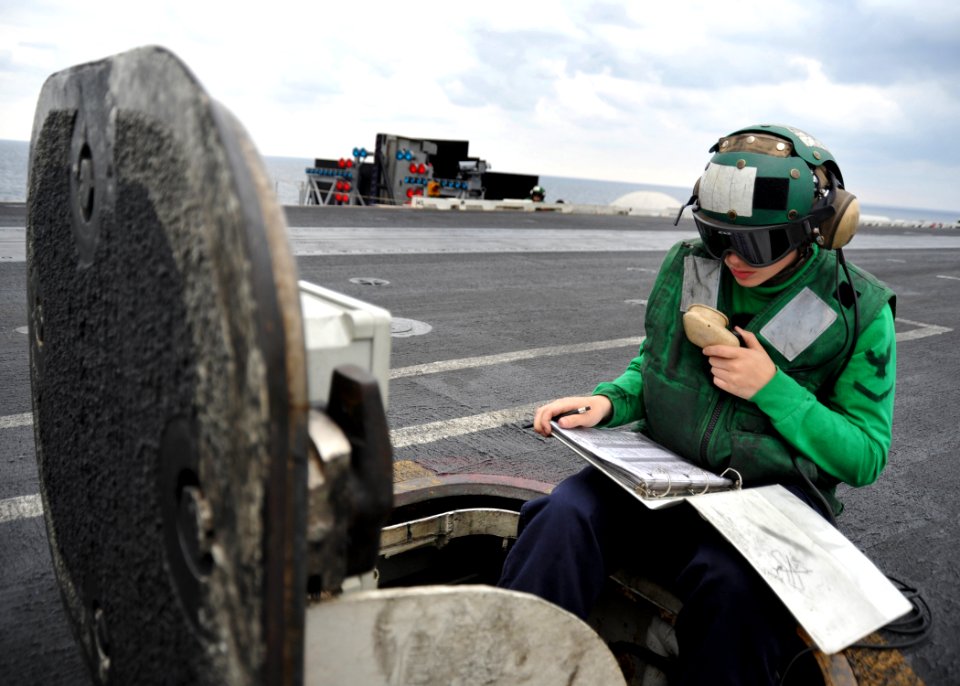US Navy 110123-N-4973M-028 Aviation Boatswain's Mate (Equipment) 3rd Class Shannon Eck speaks to catapult crew members from the center deck operato