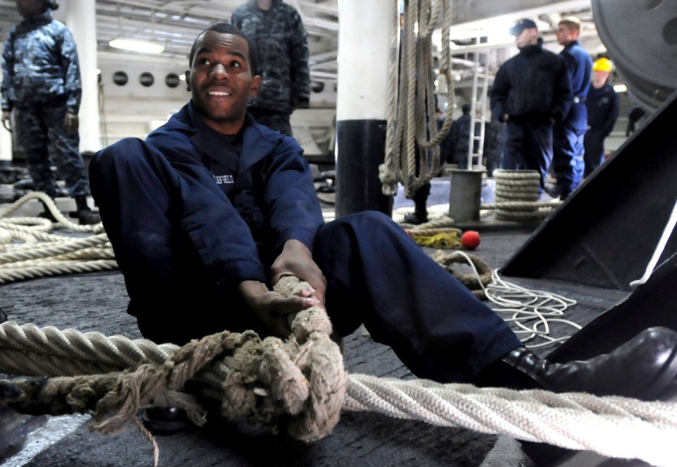 US Navy 110128-N-0864H-300 Culinary Specialist 3rd Class Brandon Troublefield passes a rat tail stopper on a mooring line aboard USS Blue Ridge (LC