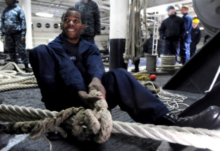 US Navy 110128-N-0864H-300 Culinary Specialist 3rd Class Brandon Troublefield passes a rat tail stopper on a mooring line aboard USS Blue Ridge (LC