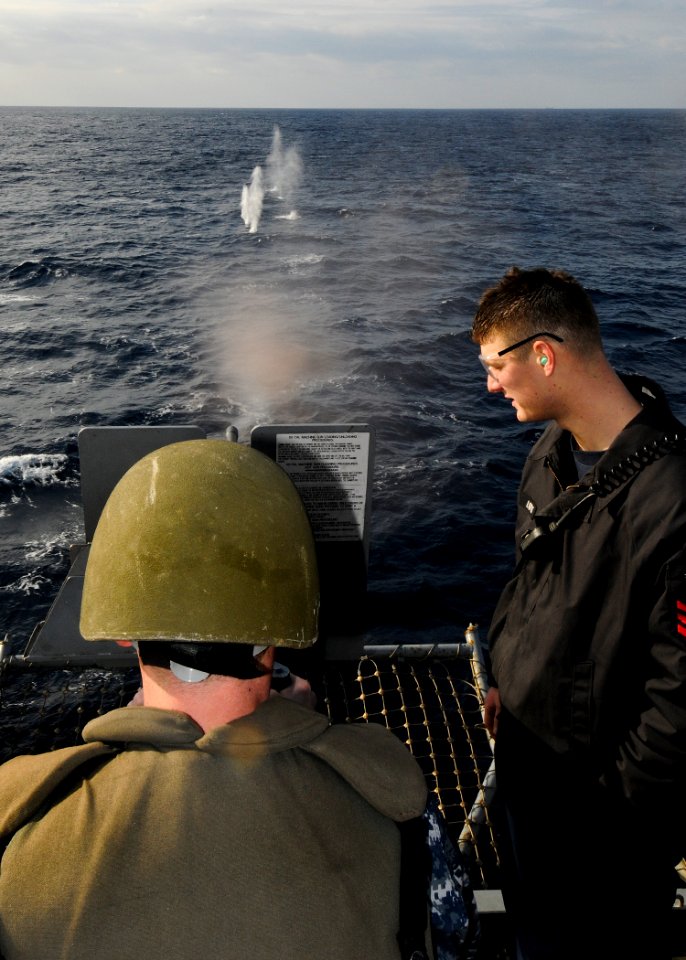 US Navy 110201-N-1512O-007 Gunner's Mate 1st Class Aaron Loftis observes Information Systems Technician 3rd Class Jared Chase during an M2HB .50-ca