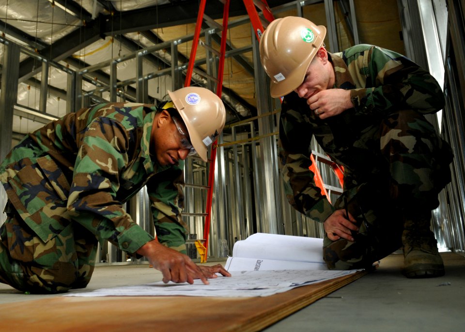 US Navy 110202-N-2218S-073 Construction Electrician 2nd Class Marvin George, left, and Engineering Aide Constructionman Andrew Chubb review blue pr