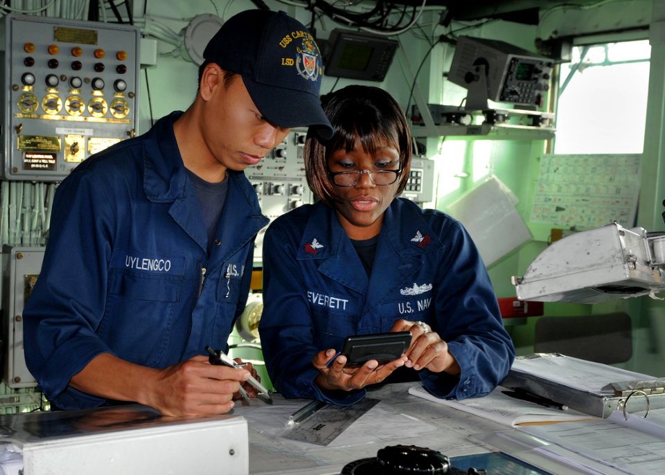 US Navy 110131-N-8069G-049 Boatswain's Mate Seaman Apprentice Verlyn Uylengco, left, and Quartermaster 1st Class Angela Everett calculate points to