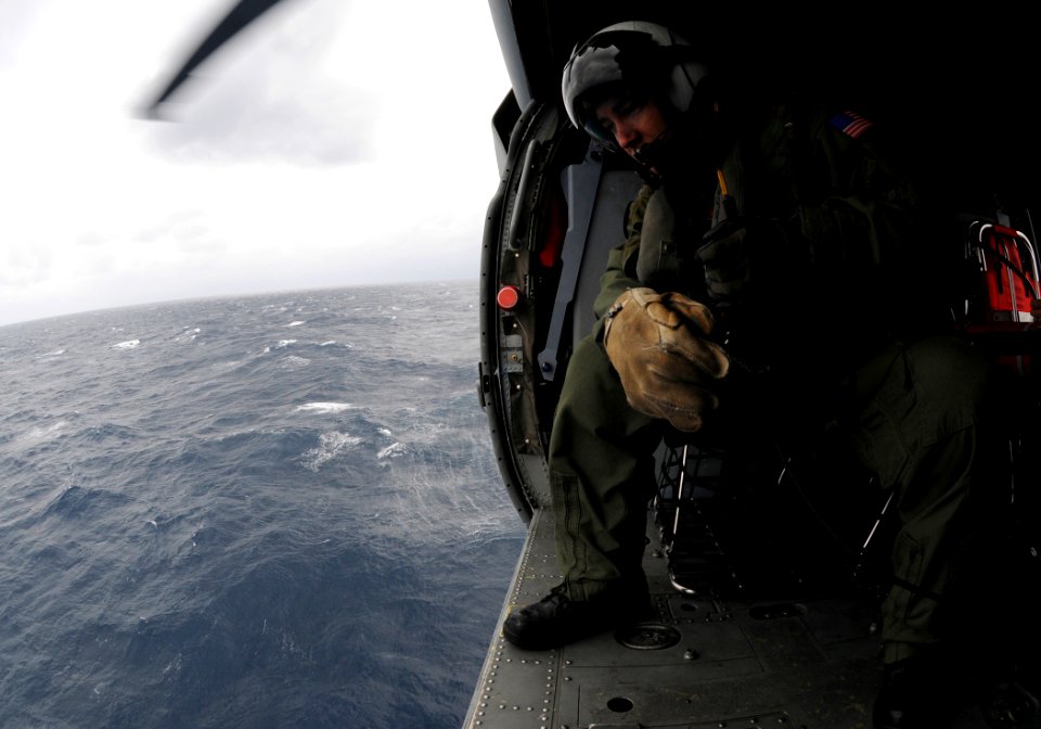 US Navy 110125-N-6632S-755 Naval Air Crewman 1st Class Curtis Clontz looks out of an MH-60S Sea Hawk helicopter