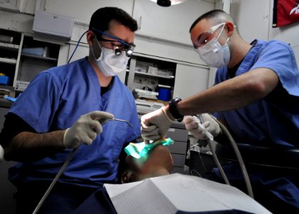 US Navy 110203-N-3620B-037 Lt. Joseph Carey, left, and Hospital Corpsman 3rd Class Eric Reid fill a cavity for a patient in the dental ward of the