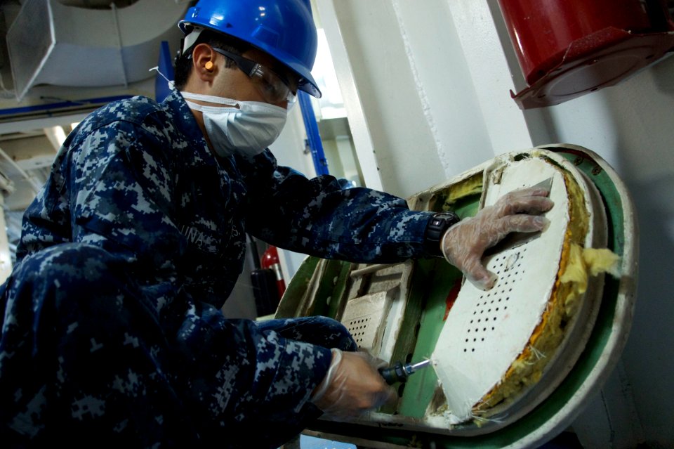 US Navy 110127-N-9643K-396 A Sailor assigned to the amphibious assault ship USS Bonhomme Richard (LHD 6) removes lagging from an airtight door