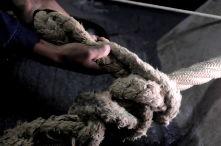 US Navy 110128-N-0864H-301 Culinary Specialist 3rd Class Brandon Troublefield passes a rat tail stopper on a mooring line aboard USS Blue Ridge (LC