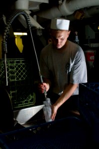 US Navy 110130-N-7488A-004 Aviation Ordnanceman Airman Johnny-Ryan Jansen washes dishes in the scullery aboard the Nimitz-class aircraft carrier US