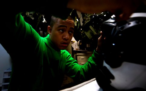 US Navy 110203-N-2055M-338 Aircrew Survival Equipmentman Airman Alan Cardinez makes his last checks on a pilot's helmet, equipped with night vision