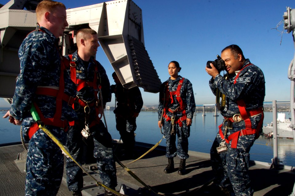 US Navy 110204-N-ZC343-474 Mass Communication Specialist 1st Class Duke Richardson photographs a reenlistment ceremony on the mast of the amphibiou