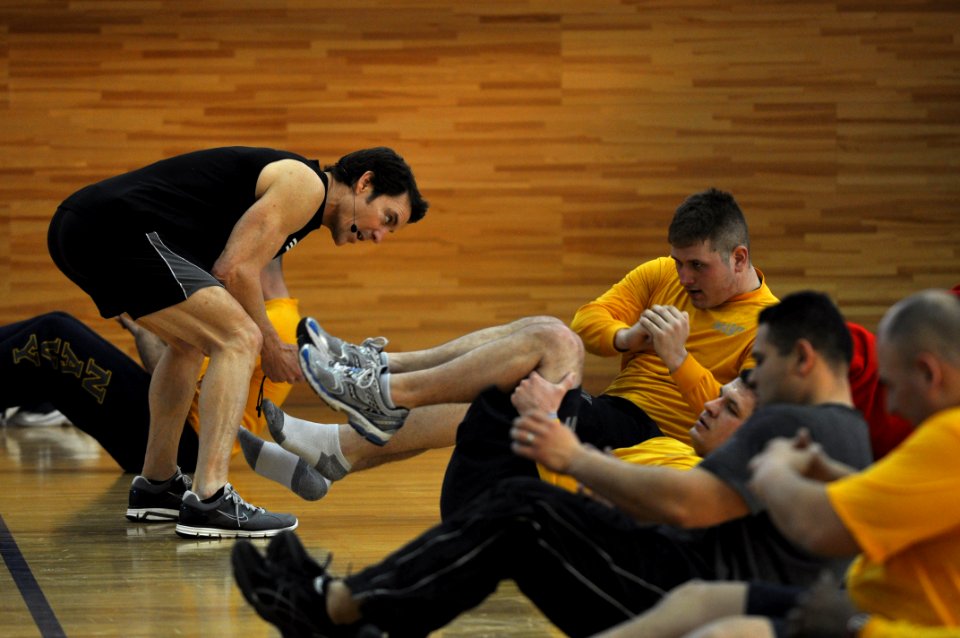 US Navy 110131-N-2013O-293 Tony Horton motivates a Sailor performing an abdominal exercise during a command physical training session at Commander